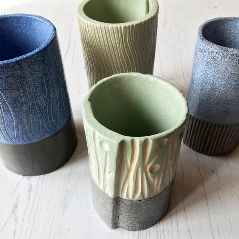 Group of eathenware cylinder pots with blue and mint crackle glazes.