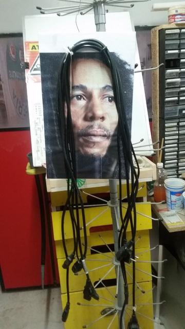 Fotografia di Bob Marley alla quale sono stati appesi alcuni cavi di alimentazione a mo' di dreads.