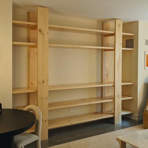 A custom bookcase built with Eastern White Pine. It has two vertical supports holding five shelves. In-between the second and third shelves is space for a television to be hung on the wall.