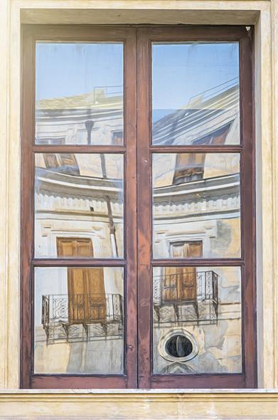 Wavy reflections of old buildings in Palermo Sicily, seen in a window in the Pratorian Palace in the historic core of the city.