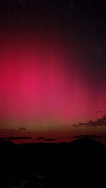 Aurora Australis, looking south from Dempster Head in Esperance, at islands. 730pm so there is a pinkish red sky, with a slight green tinge along the horizon.  Islands are black.
