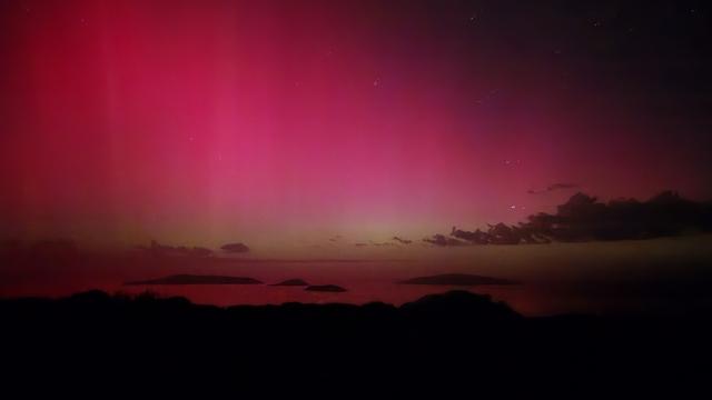 Aurora Australis, looking south from Dempster Head in Esperance, at islands. 730pm so there is a pinkish red sky, with a slight green tinge along the horizon.  Islands are black.