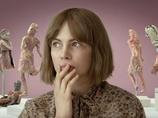 michelle williams with several small ceramic figures of women surrounding her