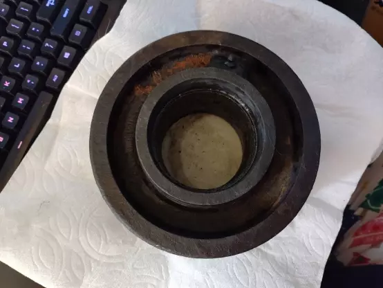 An iron wheel about 8 inches wide sitting on my desk. It has some spots of rust on it, but largely looks like it's been cleaned quite a bit. There's maybe 15% rust coverage as opposed to the 100% and then some it had before I started cleaning.