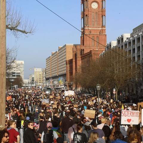 Große Menschenmenge  bei der Demonstration zum Frauenkampftag  am 8. März 2025 vor dem roten Rathaus in Berlin, das rechts im Bild zu sehen ist. Im Vordergrund hält jemand ein Plakat auf dem  steht Sisterhood.