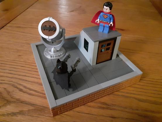 Keaton-Batman and Reeve-Superman facing off against each other on a rooftop (in LEGO)