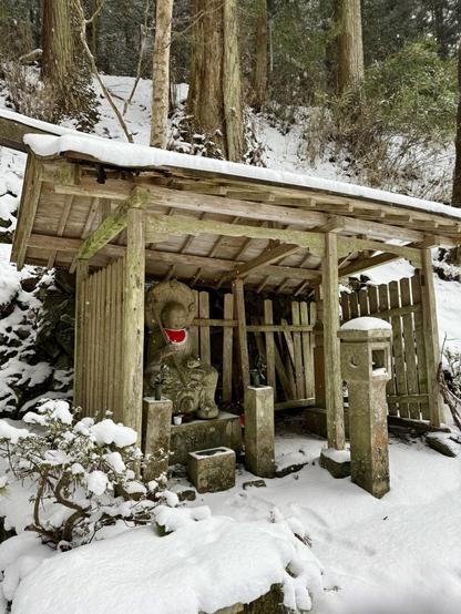 Petit sanctuaire de bois avec une statue sous la neige