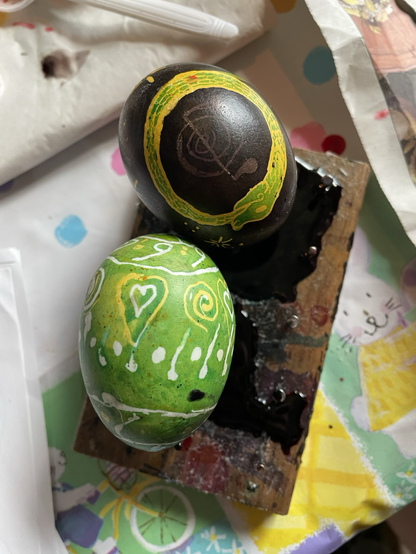 Pysanky eggs. One with a yellow and green ouroborus and a green yellow and white hearts spirals, dots and lines.
