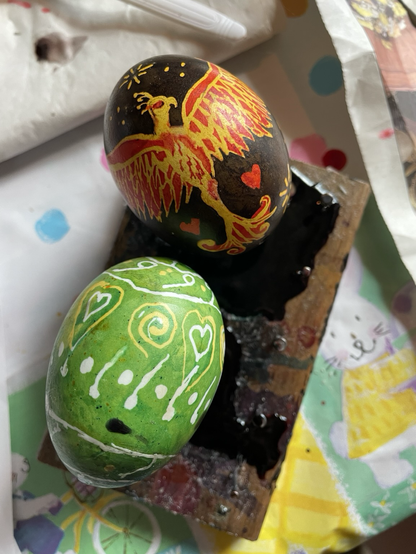 Pysanky eggs. One with a yellow and red  phoenix with red hearts and a green yellow and white hearts spirals, dots and lines.