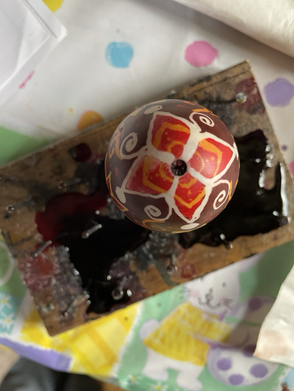 Red yellow and brown star pysanka egg with spirals, dots and knots.
