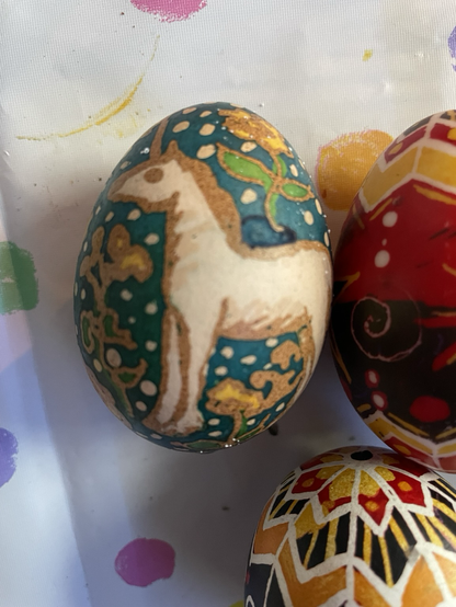 Unicorn with a teal background with yellow flowers pysanka.
