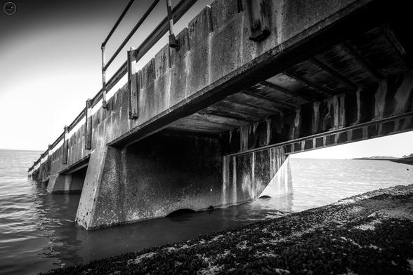 monochrome shot of concrete ramp leading into sea