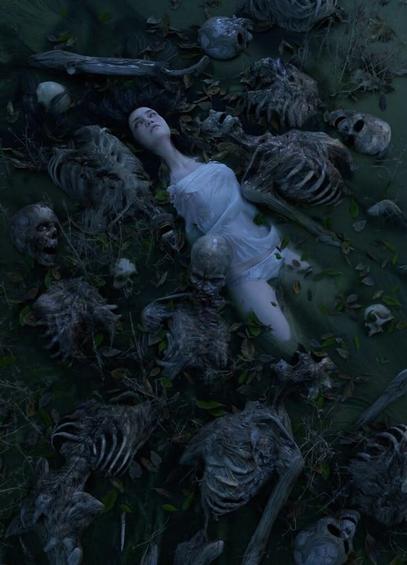 A girl lies in a river surrounded by human skeletons