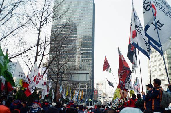 한화빌딩 앞 철탑에서 고공농성 중인 김형수 동지를 바라보는 동지들과 깃발들.