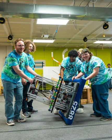 Students in the STEM Lab moving a large piece of equipment.