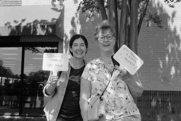 A woman and her (I think) daughter holding understated but thoughtful signs and smiling