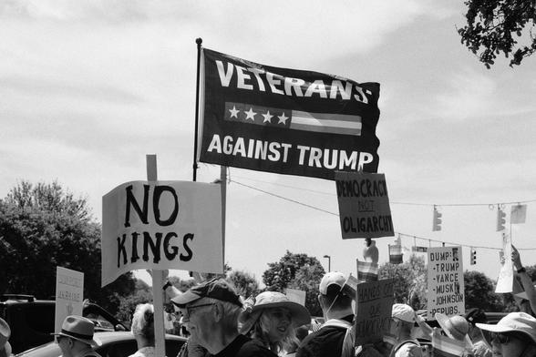 A veterans against trump flag flying in the breeze over part of the crowd