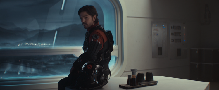 Capture écran saison 2 Star Wars Andor: 
Cassian Andor en tenue de combat impériale pour les airs devant la fenêtre d'un centre de recherche sur Siénar