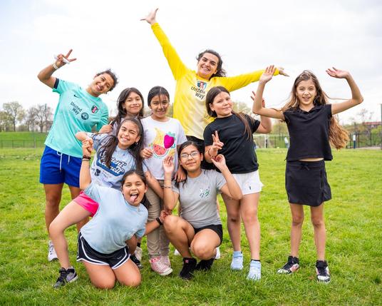 KC Current players Rocky Rodríguez and Laurel Ivory posing and smiling with the Girls on the Run group