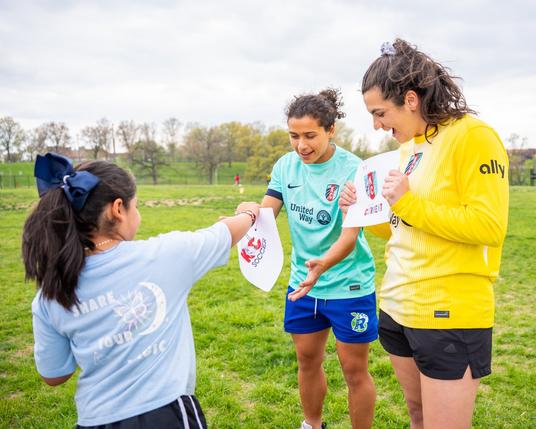 Laurel and Rocky receiving art work from a Girls on the Run participant