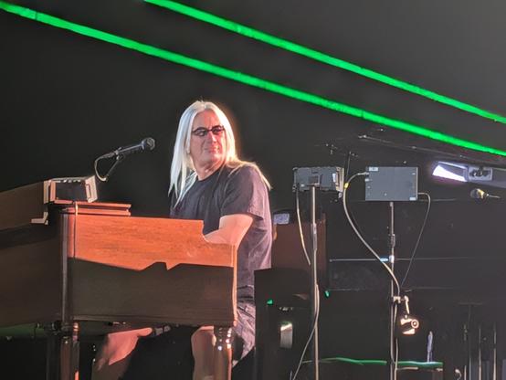 Keyboard player smiling with green beans of light behind him