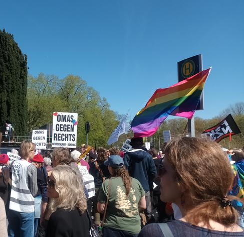 Omas gegen rechts auf der Eröffnungskundgebung in Flensburg. Eine wehende Pride Fahne und Schilder mit der Aufschrift "Omas gegen rechts".