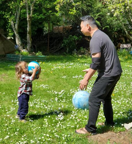 My little nephew holding a blue & white ball that smooshed his face. My brother, his Dad, is standing on the right.