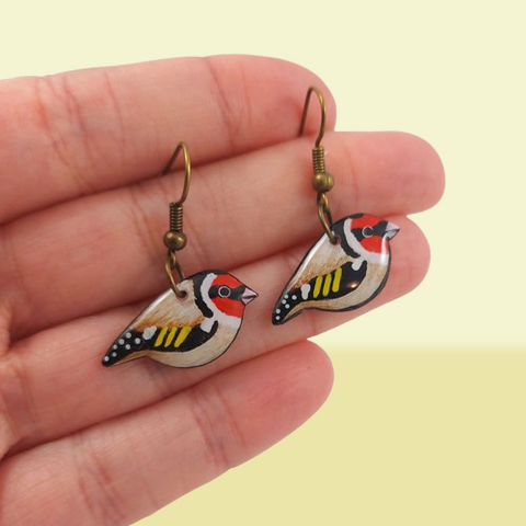 Boucles d'oreilles fantaisie pendantes éco-responsables en forme de petits chardonnerets élégants.
Les perles sont réalisées en CD recyclé, découpées et peintes à la main, puis recouvertes de résine époxy.
Les crochets sont en métal de couleur bronze, mais sont également disponibles dans d'autres coloris et types de métaux.