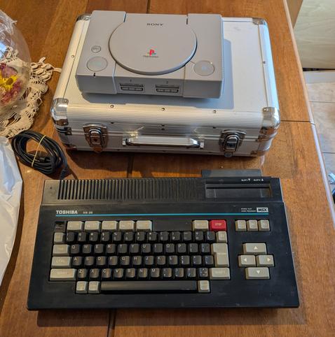 Photo of today findings at the flea market: a metal suitcase, a broken PS1, and a Toshiba HX-20