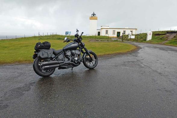Schwarzes Motorrad steht leicht bepackt, bei bewölktem Himmel auf nasser Strasse vor einem Leuchtturm.
Duncansby Head Lighthouse (Caithness/Schottland) liegt gleich "gegenüber" den Orkney Inseln.