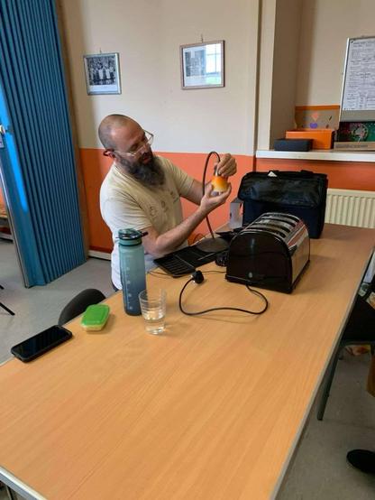 Me sat at a bench tinkering with a lamp. A toaster awaits my attention.