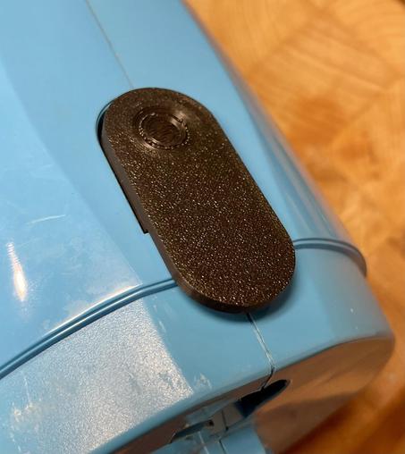 Picture showing the new latch installed on the light blue vacuum cleaner. Only the top part of the vac is shown.