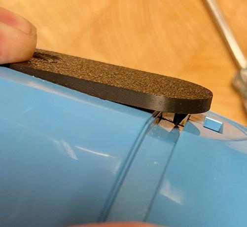 Picture showing the side view of the 2 halves of the vacuum coming together. A finger is pressing the back end of the latch which raises the other end which had a sharp latch catch on the bottom.