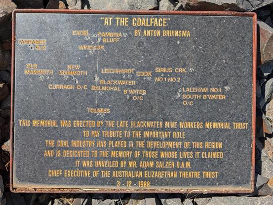 Photo of the plaque for the "At the Coalface" monument. The main part reads:

THIS MEMORIAL WAS ERECTED BY THE LATE BLACKWATER MINE WORKERS MEMORIAL TRUST TO PAY TRIBUTE TO THE IMPORTANT ROLE THE COAL INDUSTRY HAS PLAYED THE DEVELOPMENT OF THIS REGION AND IS DEDICATED TO THE MEMORY OF THOSE WHOSE LIVES IT CLAIMED. IT WAS UNVEILED BY MR. ADAM SALZER D.A.M. CHIEF EXECUTIVE OF THE AUSTRALIAN ELIZABETHAN THEATRE TRUST 3-12-1988