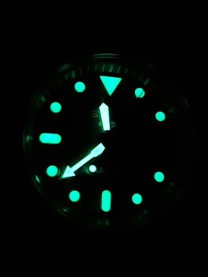 La esfera de un reloj analógico, que se ha cargado a la luz de las velas, brilla en la oscuridad. Muestra las 11 y 39 de la noche