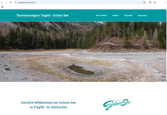 Ansicht der Website https://tragoess-gruenersee.at/
Als Haupt-Banner ist ein Foto des Grünen Sees.
Normalerweise ist hier eine sehr schöne, weitläufige und grüne Wasserfläche zu sehen, eingerahmt von Bäumen.
Derzeit zeigt das Banner ein nahezu leeres, graues Seebecken, in der Mitte lediglich eine Rest-Lacke mit wenigen cm Wasser.