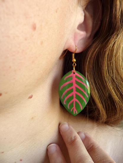 Boucles d'oreilles fantaisie pendantes éco-responsables en forme de feuilles de Fittonia vertes aux nervures roses fluo.
Les perles sont réalisées en CD recyclé, découpées et peintes à la main, puis recouvertes de résine époxy.
Les crochets sont en métal doré, et sont disponibles dans d'autres métaux et coloris.