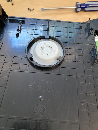 The tray spindle is a plastic disc. It is shown in its original design, sitting inside of the top DVD tray.