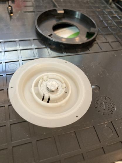 The tray spindle is a plastic disc. It is shown now with a tiny fridge magnet stuck in its center.