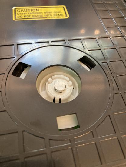 The tray spindle is a plastic disc. It is sitting back inside of the top DVD tray, now with a second magnet attached to it.