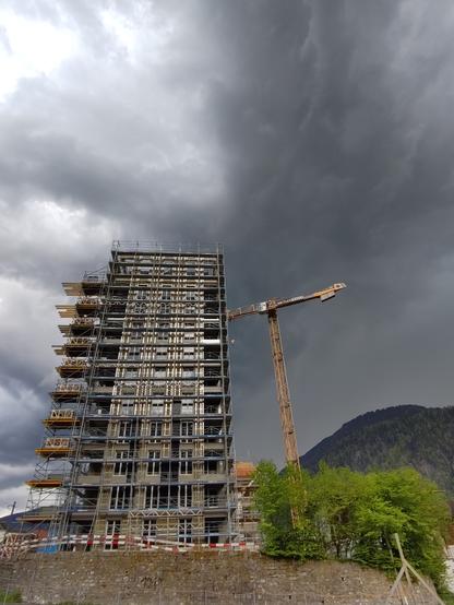 Foto. Ein eingerüstetes Gebäude mit dunklem Himmel.