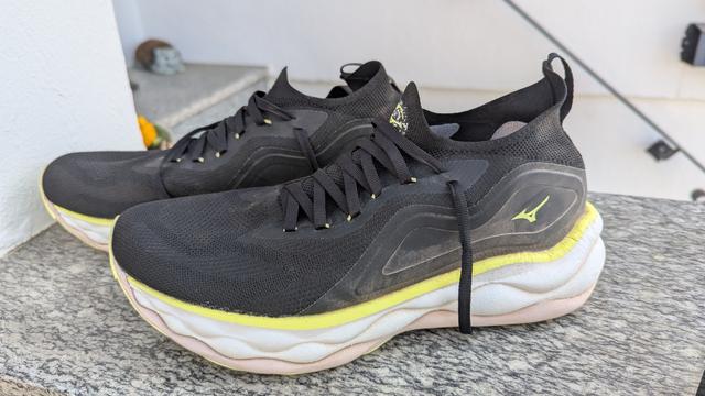 Ein paar schwarze Laufschuhe mit weißer Sohle.