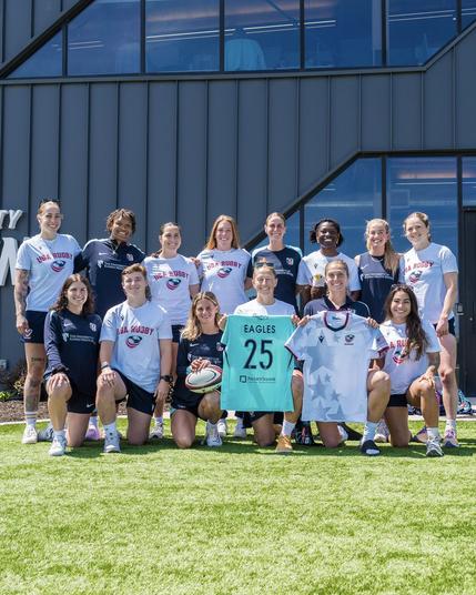 Group photo of Robinson, Izzy, Feist, Hopkins, Steigleder and Sharples with the USA Rugby Eagles with a jersey swap between both teams at The University of Kansas Health System Training Center