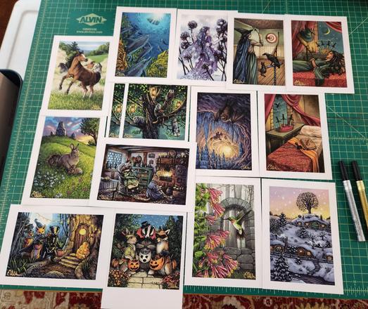 Photograph of a group of art prints by Elisabeth Alba. A mix of tarot card imagery, animals, and fantasy art.