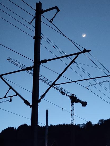 Foto. Mondsichel, Kran und Fahrleitung zur blauen Stunde.