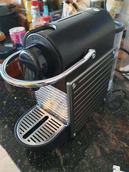 A black Nespresso Pixi coffee maker on a kitchen counter