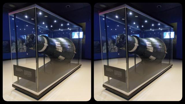 Mercury capsule in large display case, blue lighting.
