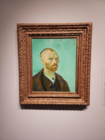 An 1888 self portrait by van Gogh. He wears two layers of brown coat with a white collar shirt. Hair is very short, beard fairly short. He looks to the right, but not at us. There is a turquoise background.