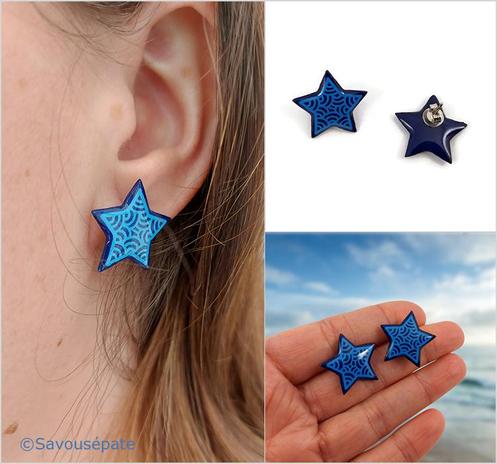 Puces d'oreilles éco-responsables en forme d'étoiles bleues marine ornées de volutes bleues ciel.
Les perles sont réalisées en CD recyclé, découpées et peintes à la main, puis recouvertes de résine époxy.
L'image est scindée en 3 parties : 
- à gauche, on voit la puce d'oreille portée.
- en haut à droite, les puces d'oreilles sont posées sur une surface plane blanche. L'une d'elle est retournée pour que l'on voit l'attache à l'arrière.
- en bas à droite, les puces d'oreilles sont tenues entre les doigts tendus d'une main