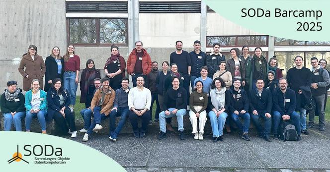 Das Bild zeigt eine Gruppe von etwa 40 Personen, die am SODa Barcamp teilgenommen haben, vor einem Gebäude mit großen Fenstern und einem grauen Betonfassaden stehen. Die Personen sind in mehreren Reihen angeordnet, einige sitzen auf einer niedrigen Mauer, während andere stehen.